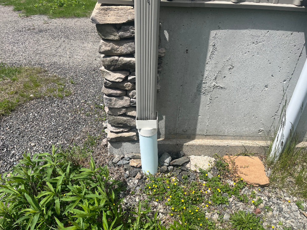 In ground gutter drainage pipe with downspout bringing gutter debris that can clog.