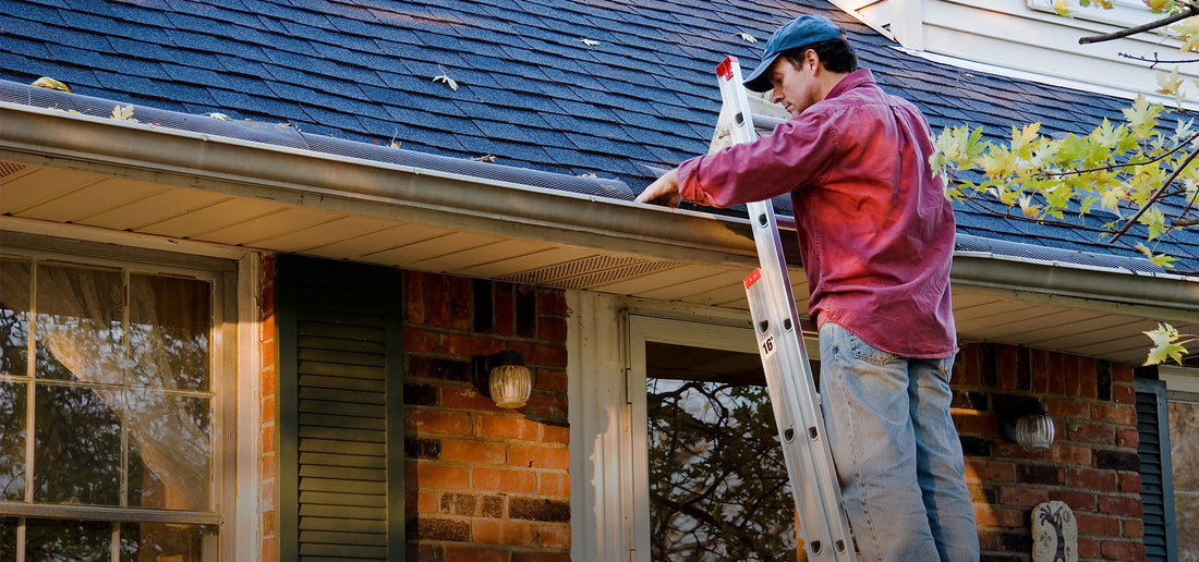 homeowner on ladder working on gutter