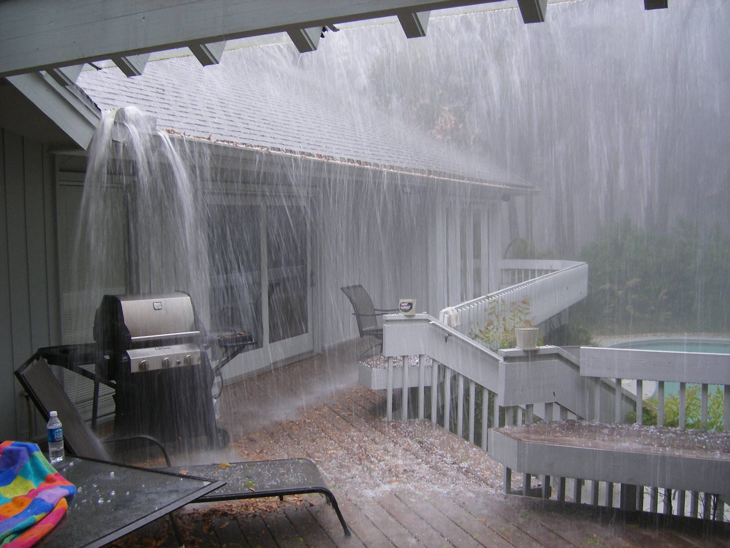 rain water overflowing a clogged gutter splashing down on deck furniture